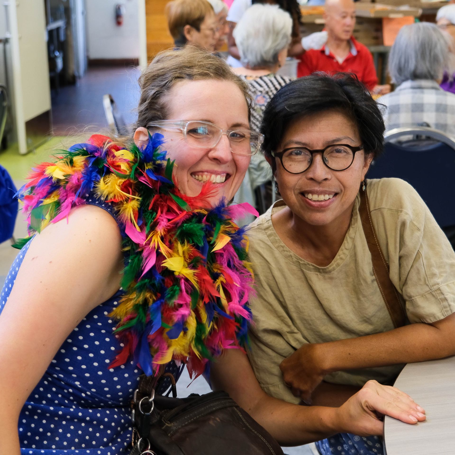 A person smiling with a feather boa around her neck Description automatically generated